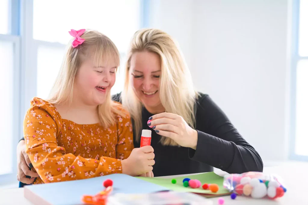 Support worker doing arts and craft with young disabled girl